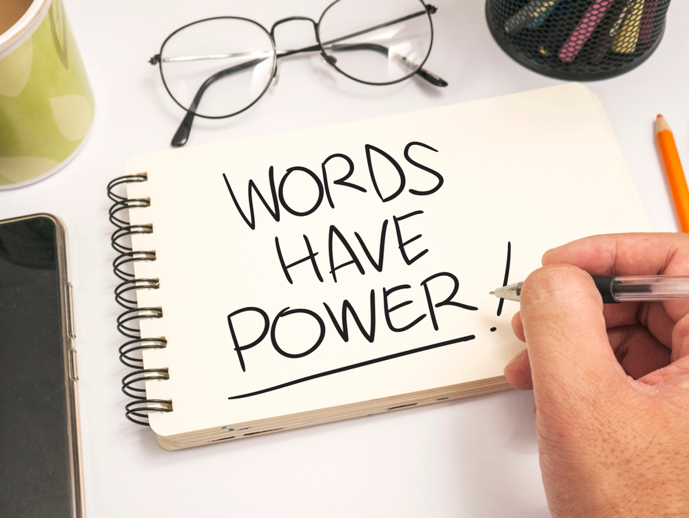 Notepad with the words 'WORDS HAVE POWER' written in pen. Glasses sit above.